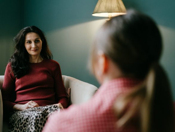 Two women in armchairs are sitting and talking. Woman psychologist practicing with patient women. Coach session between girlfriends. Therapist's gestures. Female talking in the office